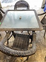 Square glass-top wicker table with surrounding chairs