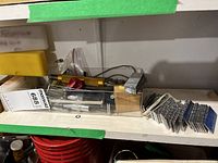 Shelf view with clear case containing punch set, stacks of lead slugs, plastic tubes