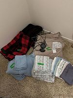 Group view of all blankets and sheet sets folded on carpet