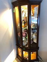 Full view of corner display cabinet showing glass doors, shelves, and lower compartment