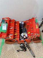 Overall view of open orange tackle box showing rod, reel, lure selection
