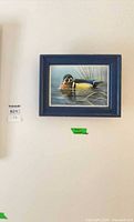Wall art in blue frame featuring wood duck on water