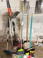 Group view of trimmer, shovels, rakes, brooms, sprays on garage floor