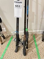 Three rods with reels standing in lot