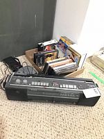 Lot overview showing Sony boombox, box of DVDs, Kenwood CD player with adapter