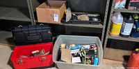 Shelf with red toolbox, clear tote of light bulbs, black toolbox, cardboard box of hardware