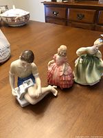 Three Royal Doulton figurines front view on table