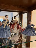 Three Royal Doulton figurines inside display cabinet