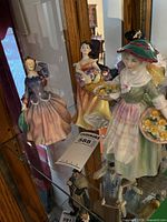 All three Royal Doulton figurines on glass shelf