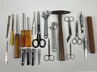 All items laid out including hammer, wrenches, screwdrivers, scissors, nail tools, pencils