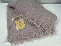 Folded lavender mohair blanket showing fringe and attached paper tag