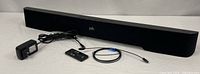 Full view of soundbar with remote, power adapter and optical cable