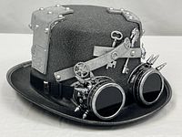 Front and side view of gray felt top hat with goggles and steampunk accents