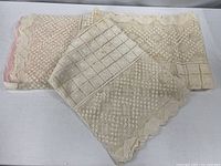 Folded cream lace tablecloth showing scalloped edge and overall pattern