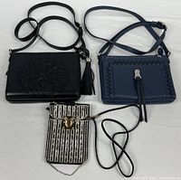 Three purses laid out: black embossed, navy whip-stitch, patterned phone pouch