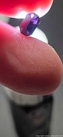 Octagon-cut deep purple spinel held between fingers showing pavilion facets