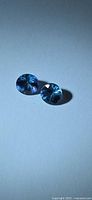 Pair of round faceted blue-violet tanzanite stones on white background