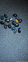 Loose oval black opals on textured black background