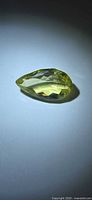 Pear-shaped lemon citrine side view under spotlight