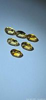 Six oval golden citrine gems arranged on neutral background