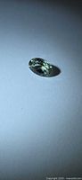Oval-cut mint green tourmaline on neutral background, angled view