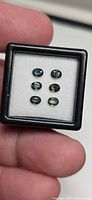 Six oval tri-colored sapphires in display case