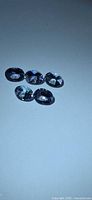 Five oval faceted tanzanite stones on light background