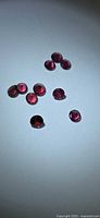 Nine round rhodolite garnets grouped on light background