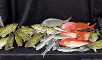 array of green spotted, grey, and orange-red faux fish displayed on black backdrop