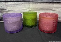Front view of all three colored candles with lids on