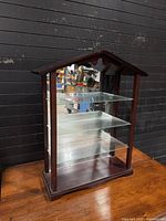 Front view of wood display cabinet with glass shelves and mirrored back
