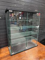 Front view of glass cabinet showing five shelves and sliding doors