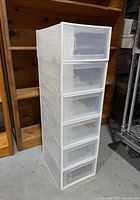 Full stack of six white plastic shoe boxes