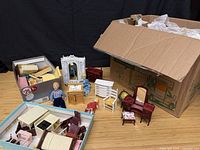 Overview of open box, trays, visible dollhouse furniture and dolls