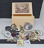 Overall view of wooden box open with assorted jewelry spread in front