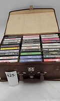 Open brown carrying case showing rows of cassette tapes