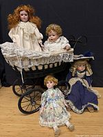 Group view of four dolls posed with wicker carriage