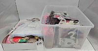 Wide view of tray and plastic bin containing loose and packaged doll clothes
