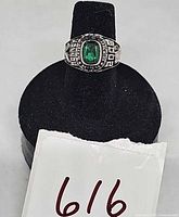 Front view of ring showing green stone and bezel text