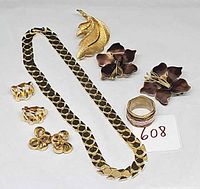 All items laid out: necklace, leaf brooch, enamel flower earrings, bow earrings, extra earrings, ring