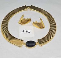 Necklace laid in circle with earrings inside, shows overall design and condition
