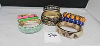 All eight goldtone enamel clamper bracelets arranged upright