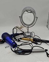 Group shot of mirror, hair dryer, curling iron, heated brush