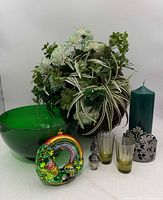 Group view of all items: floral arrangement, green bowl, candle with sleeve, ornament, two glasses, stopper