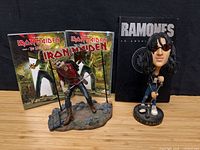 Group shot of Eddie figurine, Joey Ramone bobblehead, Ramones book, two Iron Maiden DVDs