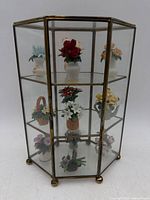 Front view of brass and glass cabinet with all miniature flower figurines visible