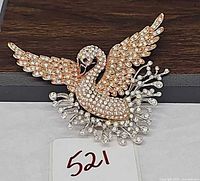 Front view of rose-gold crystal swan brooch, wings spread, silver-tone crystal spray visible