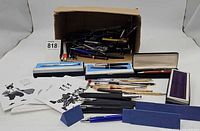 Overview of lot showing cardboard box with assorted pens, Cross boxes, cases and note cards