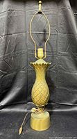 Full view of brass pineapple lamp with harp and finial