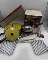 Group shot of all items including fondue set box, electric knife, yellow cookware, trivets
